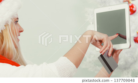 Woman in Santa hat holding tablet and credit card 137709848