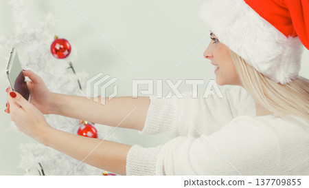 Girl in santa hat taking picture of herself using phone 137709855