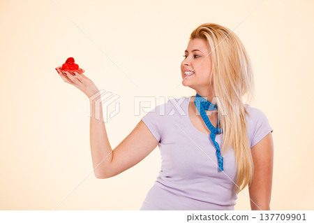 Woman with measuring tape holding sweet cupcake Woman with measuring tape holding sweet cupcake 137709901