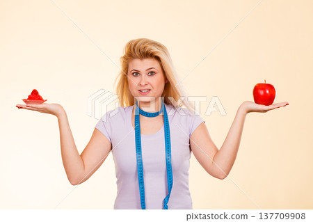 Woman with measuring tape choosing what to eat Woman with measuring tape choosing what to eat 137709908