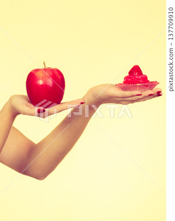 Woman hand holding apple and sweet cupcake Woman hand holding apple and sweet cupcake 137709910
