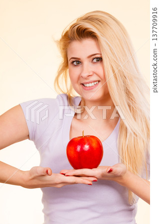 Happy woman holding delicious red apple Happy woman holding delicious red apple 137709916