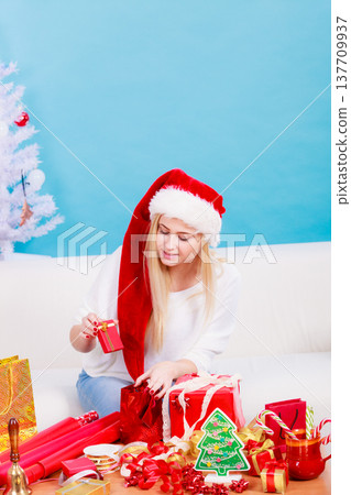 Woman in Santa hat preparing christmas gifts Woman in Santa hat preparing christmas gifts 137709937
