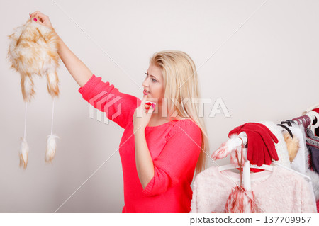 Woman in wardrobe holding furry hat Woman in wardrobe holding furry hat 137709957