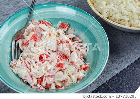 Bowl of creamy crab stick mixture with mayonnaise and cream cheese in white ceramic bowl. Preparation stage for homemade sushi rolls and onigiri filling. Fresh ingredients on kitchen table Bowl of creamy crab stick mixture with mayonnaise and cream cheese in white ceramic bowl. Preparation stage for homemade sushi rolls and onigiri filling. Fresh ingredients on kitchen table 137710293