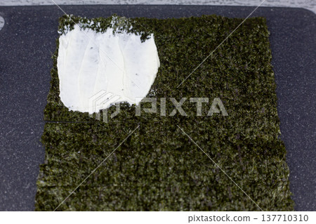 Nori sheet with cream cheese spread on one quarter. Healthy protein rich filling for light Japanese style snack. Perfect for low carb diet and clean eating enthusiasts Nori sheet with cream cheese spread on one quarter. Healthy protein rich filling for light Japanese style snack. Perfect for low carb diet and clean eating enthusiasts 137710310