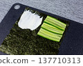 Crisp cucumber slices layered on nori second quarter beside creamy cheese. Contrast of smooth and crunchy textures in homemade sushi sandwich. Fresh ingredients shine in natural light 137710313