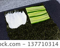 Nutritious cucumber slices added to nori quarter with cream cheese. Low calorie vegetable boost for homemade sushi sandwich. Perfect for health conscious cooks seeking fresh, light meal option 137710314
