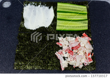 Balanced portions of cream cheese, cucumber, and crab on nori quarters. Each ingredient perfectly proportioned for harmonious bite. Visual guide to building well balanced sushi sandwich Balanced portions of cream cheese, cucumber, and crab on nori quarters. Each ingredient perfectly proportioned for harmonious bite. Visual guide to building well balanced sushi sandwich 137710317