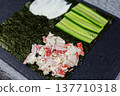 Nori sheet quarters topped with cream cheese, cucumber slices, and crab mixture. Colorful Japanese inspired appetizer bites perfect for parties. Elegant finger food presentation on dark surface 137710318