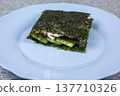 Beautifully folded sushi sandwich centered on plate. Nori wrapping contrasts with colorful filling. Aesthetic presentation perfect for food photography and recipe blogs 137710326