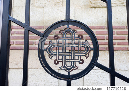 A finely crafted metal emblem mounted on a gate, featuring geometric curves and loops in a Celtic-inspired design A finely crafted metal emblem mounted on a gate, featuring geometric curves and loops in a Celtic-inspired design 137710528