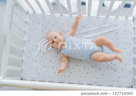 Baby lying peacefully in a cozy crib at home, feeling safe and calm in a warm nursery atmosphere. Simple everyday moment of care and comfort. Infant sleep, early childhood and gentle parenting concept Baby lying peacefully in a cozy crib at home, feeling safe and calm in a warm nursery atmosphere. Simple everyday moment of care and comfort. Infant sleep, early childhood and gentle parenting concept 137710565