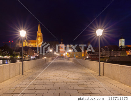 Stone Bridge and cathedral at night in Regensburg on Danube River Germany 137711375