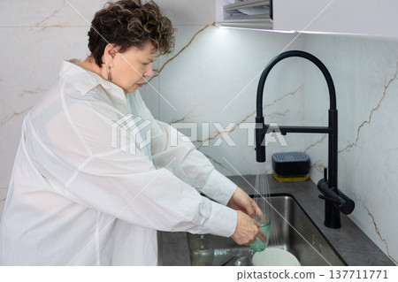 Senior woman cleaning kitchen countertop at home Senior woman cleaning kitchen countertop at home 137711771