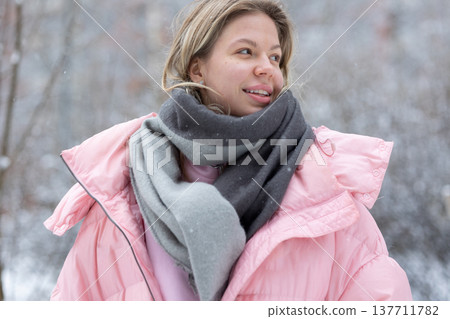 Smiling young blonde woman in pink winter jacket outdoors Smiling young blonde woman in pink winter jacket outdoors 137711782