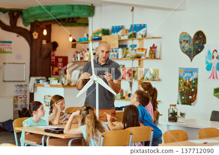 Teacher demonstrating a wind turbine model to engaged elementary students in a colorful classroom science lesson Teacher demonstrating a wind turbine model to engaged elementary students in a colorful classroom science lesson 137712090