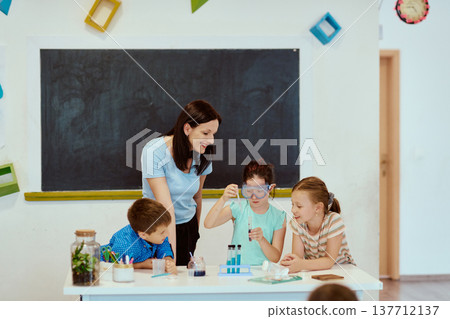 Teacher guiding children through a hands-on science experiment in a bright elementary classroom Teacher guiding children through a hands-on science experiment in a bright elementary classroom 137712137