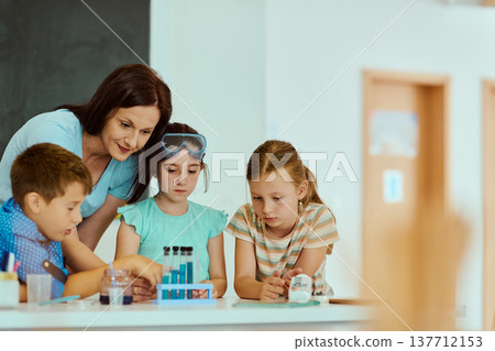Teacher guiding students through a hands-on science experiment in an elementary classroom 137712153