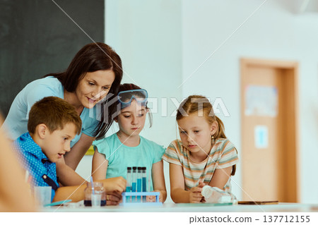 Teacher guiding elementary students through a hands-on science experiment in a bright classroom Teacher guiding elementary students through a hands-on science experiment in a bright classroom 137712155