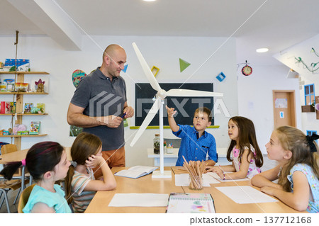 Teacher and elementary students exploring a model wind turbine during a hands-on classroom science lesson Teacher and elementary students exploring a model wind turbine during a hands-on classroom science lesson 137712168