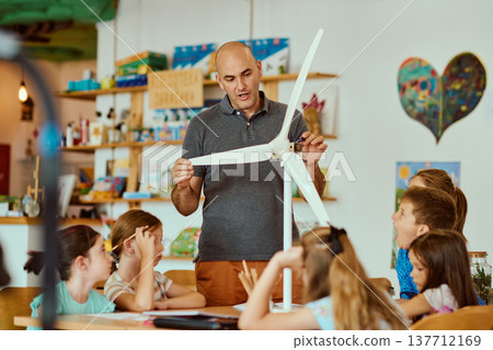 Teacher demonstrating a model wind turbine to children in a hands-on STEM classroom lesson on renewable energy Teacher demonstrating a model wind turbine to children in a hands-on STEM classroom lesson on renewable energy 137712169