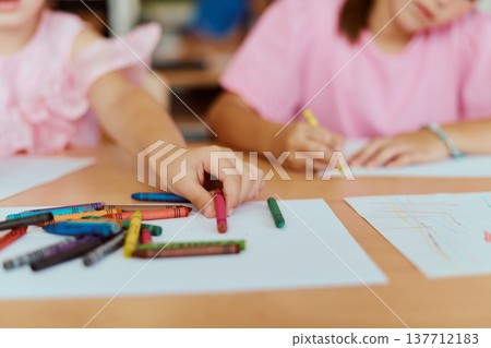Children drawing with crayons at a classroom table, creative kids making colorful artwork together Children drawing with crayons at a classroom table, creative kids making colorful artwork together 137712183