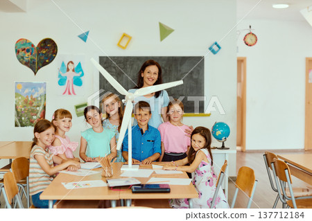 Teacher and primary school students building a wind turbine model during a hands-on STEM lesson in classroom 137712184