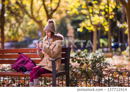 woman with eating disorders sitting on park bench using smartphone 137712914