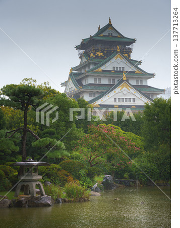 Osaka, Japan - Sep 22 2024, panoramic view of Osaka Castle on a rainy day, in the foreground a park with a pond with a heron in it, cloudy sky, daytime, Osaka, Japan Osaka, Japan - Sep 22 2024, panoramic view of Osaka Castle on a rainy day, in the foreground a park with a pond with a heron in it, cloudy sky, daytime, Osaka, Japan 137713264