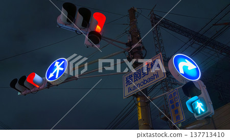 Osaka, Japan - Sep 22 2024, panoramic view from below of road signs with a man and an arrow and road and pedestrian traffic lights on a pillar, in the background dark night sky, Osaka, Japan Osaka, Japan - Sep 22 2024, panoramic view from below of road signs with a man and an arrow and road and pedestrian traffic lights on a pillar, in the background dark night sky, Osaka, Japan 137713410