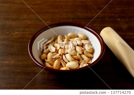 桌子背景中,研缽和研杵裡裝著花生。 桌子背景中,研缽和研杵裡裝著花生。 137714270