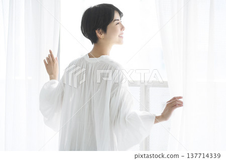 一位年輕女子像往常一樣拉開窗簾，向外望去。 137714339