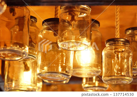 Vintage glass jars on the ceiling in the store in the evening. Light through the glass of the jar.    137714530