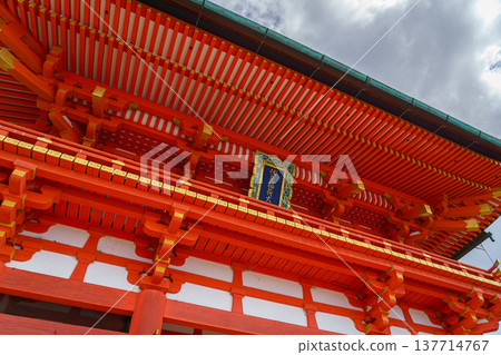 Kyoto, Japan - Sep 23 2024, panoramic view from below of the red facade of the Fushimi Inari Temple building with a roof cornice, with a cloudy sky in the background, Kyoto, Japan 137714767