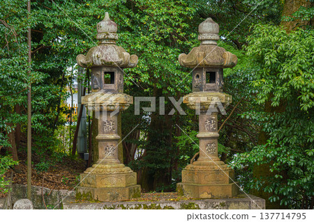 Kyoto, Japan - Sep 23 2024, close up view of two stone lanterns with green foliage of trees in the background, Fushimi Inari Temple, at daytime, without people, Kyoto, Japan Kyoto, Japan - Sep 23 2024, close up view of two stone lanterns with green foliage of trees in the background, Fushimi Inari Temple, at daytime, without people, Kyoto, Japan 137714795