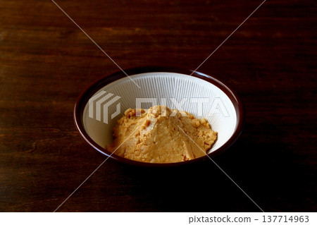 Homemade peanut butter ground in a mortar and pestle, shown in the background of the table. Homemade peanut butter ground in a mortar and pestle, shown in the background of the table. 137714963