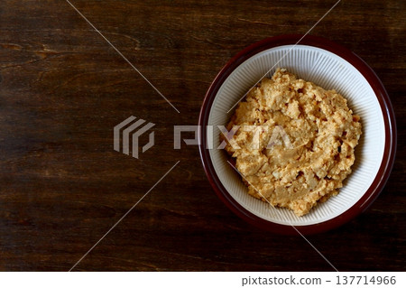 Homemade peanut butter ground in a mortar and pestle, shown in the background of the table. Homemade peanut butter ground in a mortar and pestle, shown in the background of the table. 137714966