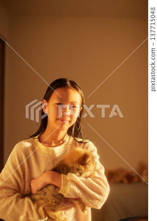 A cute middle school girl basking in the morning sunlight in her bedroom, holding a puppy. A cute middle school girl basking in the morning sunlight in her bedroom, holding a puppy. 137715048