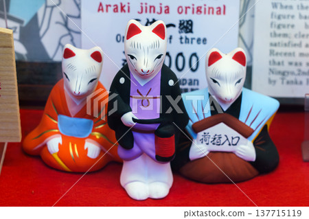 Kyoto, Japan - Sep 23 2024, A close-up view of three small figures of white kitsune foxes with red ears dressed in traditional Japanese clothes at a souvenir shop at Fushimi Inari Temple, Kyoto, Japan Kyoto, Japan - Sep 23 2024, A close-up view of three small figures of white kitsune foxes with red ears dressed in traditional Japanese clothes at a souvenir shop at Fushimi Inari Temple, Kyoto, Japan 137715119
