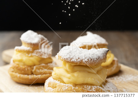 Sprinkle powdered sugar on top of homemade cream puffs to finish them off. 137715377