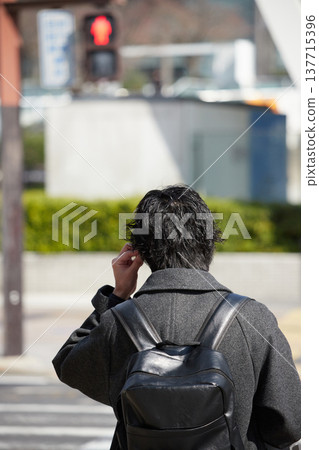 冬日的白天,一位年輕的上班族在名古屋市中心的十字路口等紅燈。 冬日的白天,一位年輕的上班族在名古屋市中心的十字路口等紅燈。 137715396