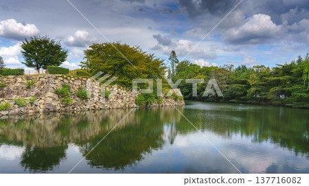 Himeji, Japan - Sep 24 2024, panoramic view of pond with mirrored water, bridge in front of fortress wall of Himeji Castle, White Heron Castle, at daytime, without people, Himeji, Japan 137716082