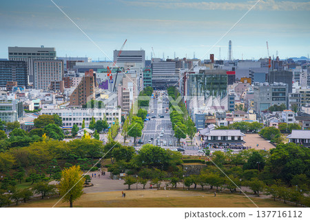 Himeji, Japan - Sep 24 2024, panoramic aerial view from window of White Heron Castle to park in front of castle and city of Himeji, with people on courtyard, at daytime with cloudy sky, Himeji, Japan 137716112