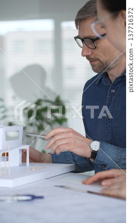 Architects collaborating on architectural plans. Designing modern building models. Drawing blueprints. Engineering innovative residential project solutions 137716372