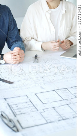 Architects collaborating on architectural project, discussing building design plans, creating new house models, developing urban construction schemes, working in modern office 137716433