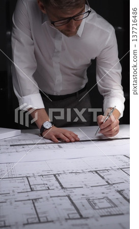 Architect drawing floor plan blueprint with ruler and pen, designing new building construction project. Concept of architecture and business in low key lighting 137716486