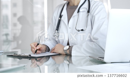 Doctor writing prescription or medical record, providing patient care and healthcare services in clinic. Medicine and health care 137716602