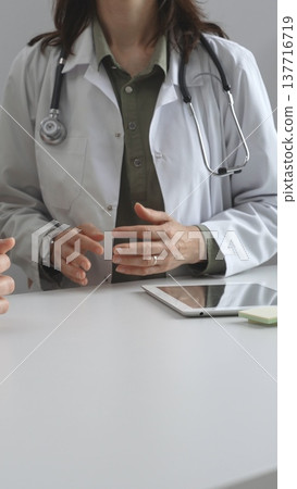Doctor woman is explaining diagnosis to male patient during a medical consultation in a medical office, gesturing with hands, vertical close up view. Medicine and health care concept Doctor woman is explaining diagnosis to male patient during a medical consultation in a medical office, gesturing with hands, vertical close up view. Medicine and health care concept 137716719