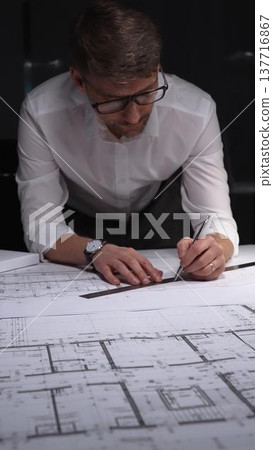 Architect drawing floor plans with ruler and pencil, creating blueprints for new building construction. Concept of architecture and business in low key lighting 137716867